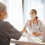 Médica com máscara atende paciente e quer saber qual é a diferença entre clínica e consultório.